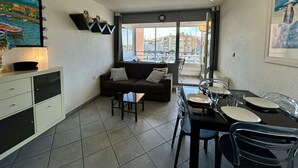 Ein kompakter Wohnbereich mit Küchenzeile, Essplatz, einer Couch und einem Deckenventilator.