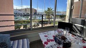 Ein Balkon mit einem Tisch für zwei Personen, mit Blick auf eine Marina mit Booten und Gebäuden.