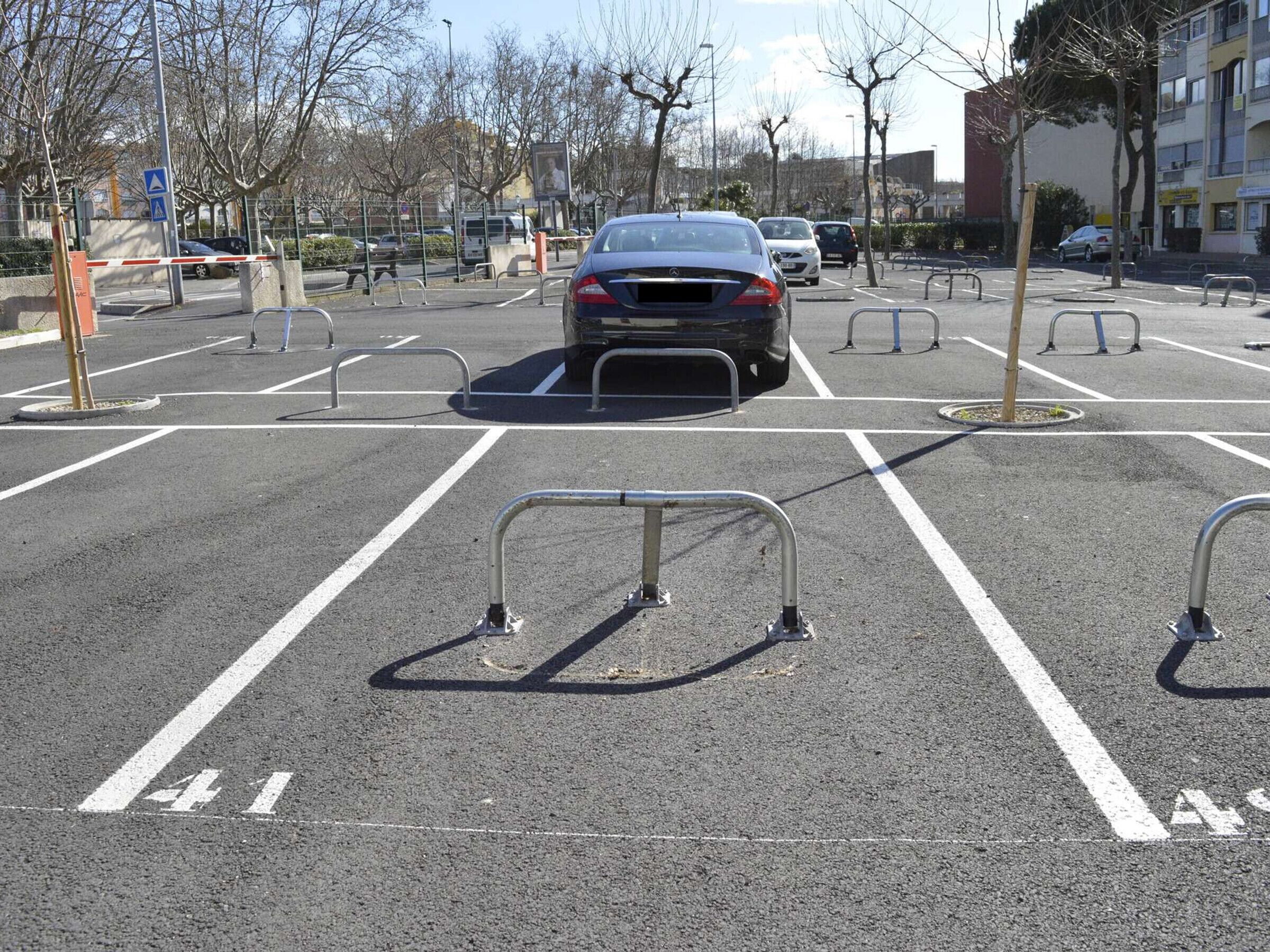 A parking lot with marked spaces, a barrier gate, and a blue directional sign.