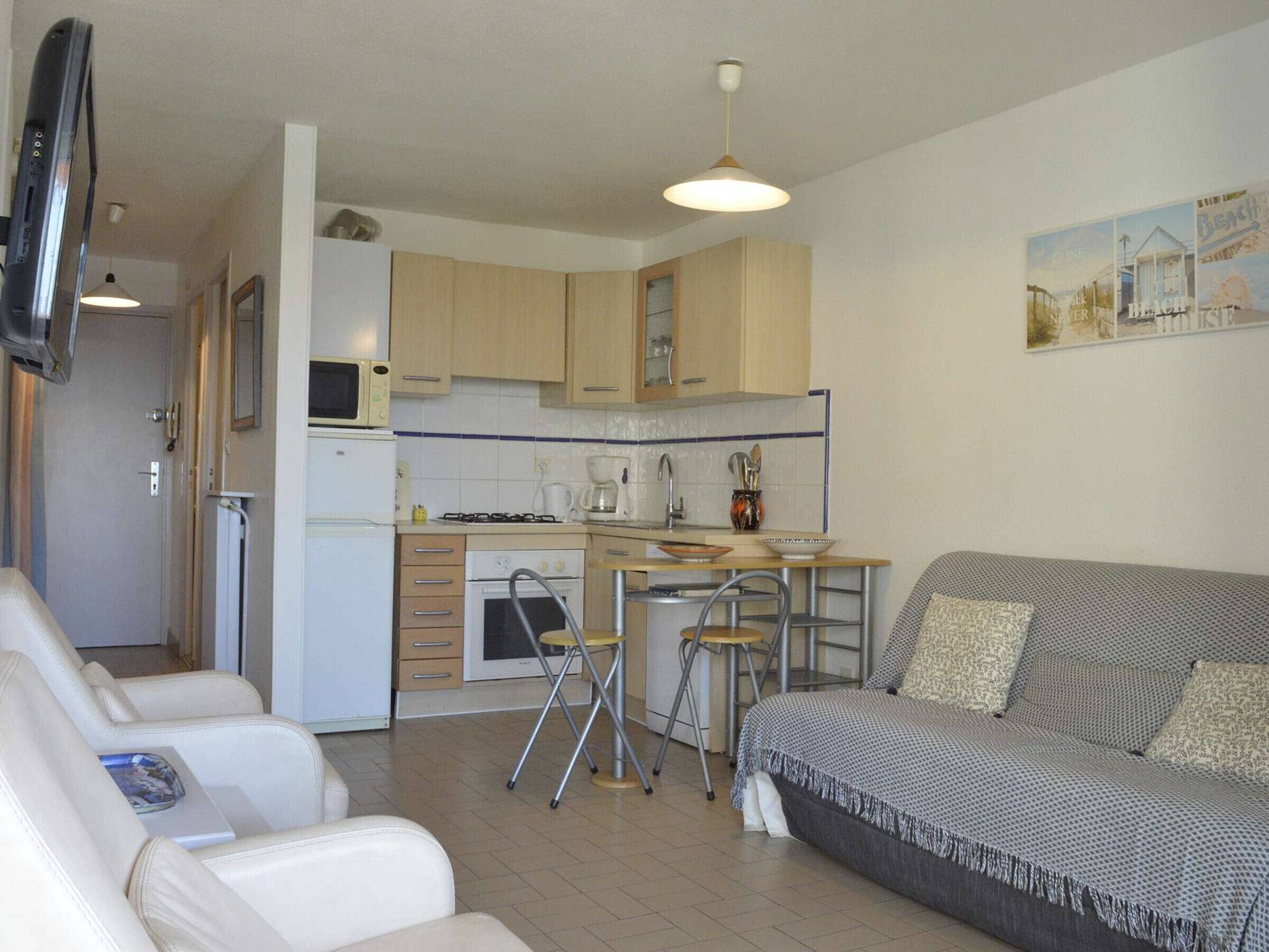 A compact living space with a kitchenette, a sofa, and a dining area.