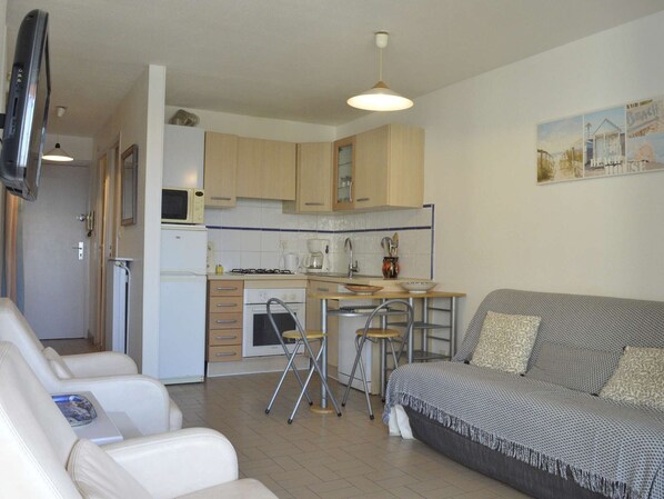 Un espacio habitable compacto con kitchenette, un sofá y zona de comedor.