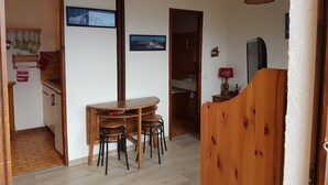 A compact kitchen with a dining area, wooden furniture, and a hanging light fixture.