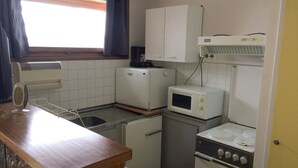 Una cocina compacta con un lavamanos, un microondas, un tostador y una estufa.