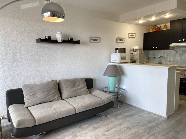 A modern kitchen with a central island, a sofa, and a lamp.