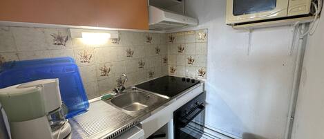 A compact kitchen with a sink, stove, and microwave.