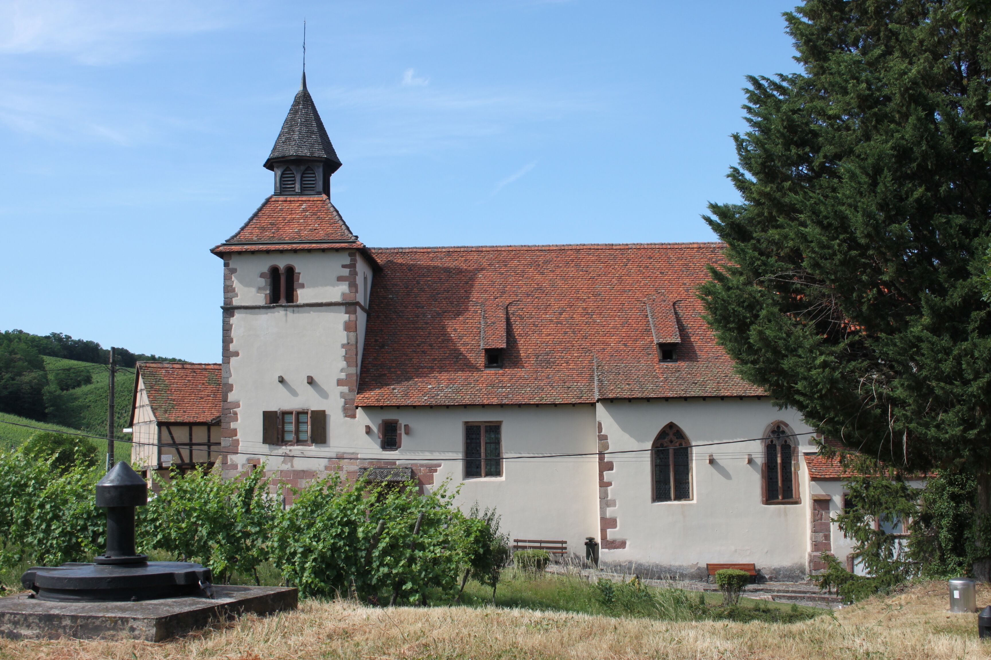 Une église dotée d’un clocher, d’une cloche et d’un petit jardin.