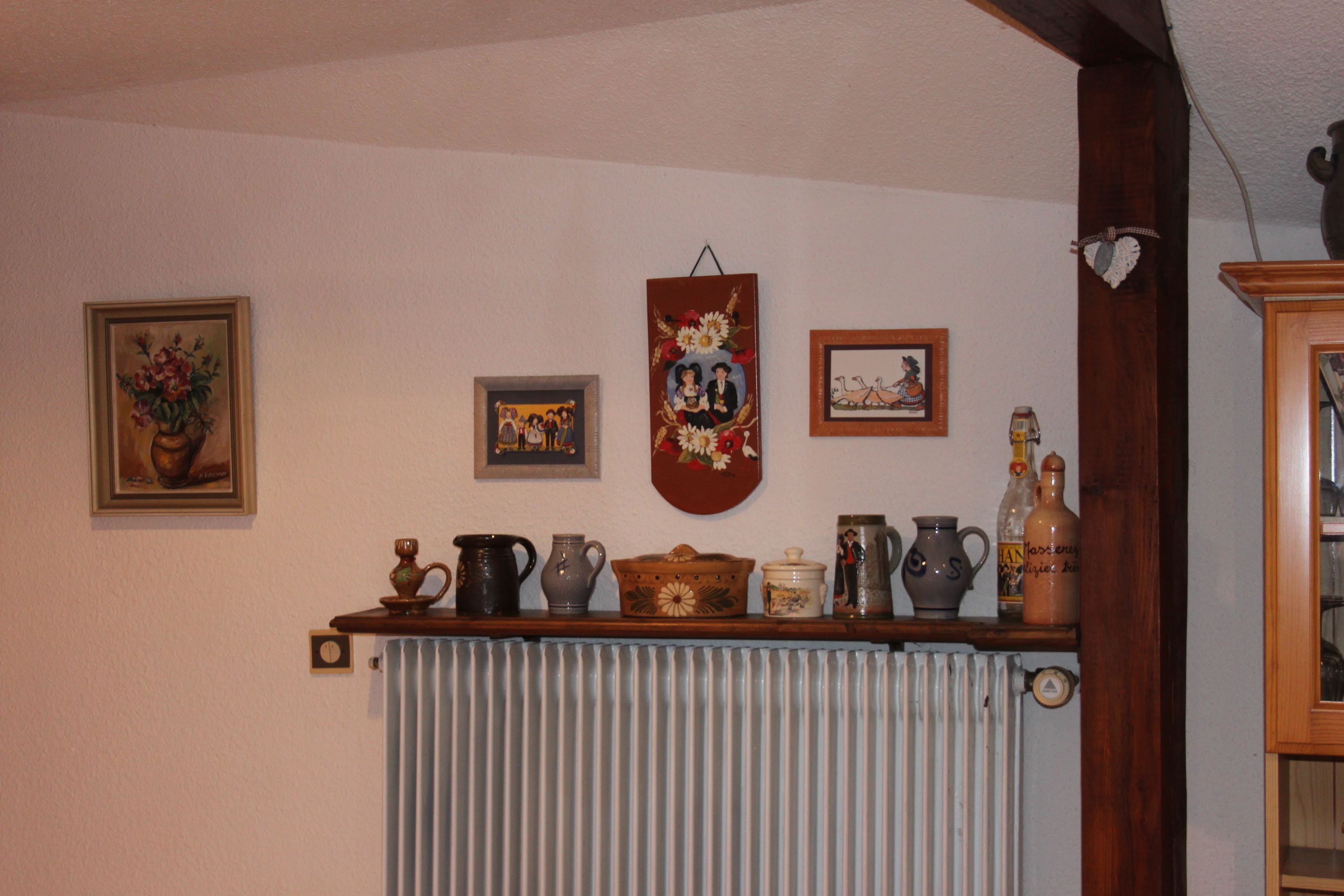 Ein Zimmer mit einem hölzernen Kaminfeuer und verschiedenen Keramikobjekten sowie gerahmten Bildern an der Wand.