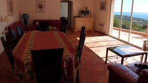 A dining area with a table set for four, a sofa, and a TV in the background. - Air-conditioned villa with heated pool, breathtaking sea view on the Levant Island (Cavalaire-Sur-Mer)