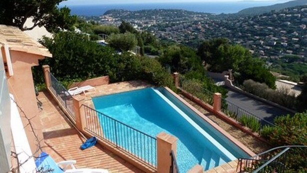 A rectangular swimming pool with a view of a coastal town and hills in the background. - Air-conditioned villa with heated pool, breathtaking sea view on the Levant Island (Cavalaire-Sur-Mer)