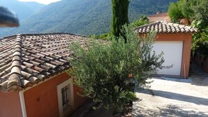 A house with a tiled roof, a garage, and a garden with a tree. - Air-conditioned villa with heated pool, breathtaking sea view on the Levant Island (Cavalaire-Sur-Mer)