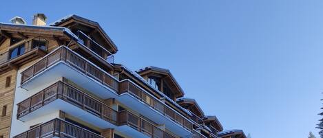Un hôtel à plusieurs étages, doté de balcons, qui offre une vue sur un paysage enneigé.