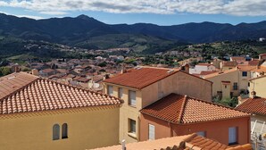 A town with terracotta-roofed buildings, a mountainous backdrop, and a clear sky. - Studio in Banyuls-sur-Mer, terrace close to beaches (Banyuls-sur-Mer)