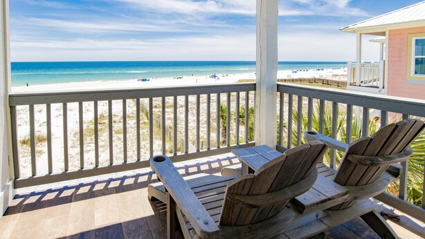 A wooden deck with two Adirondack chairs overlooking a beach with a clear sky. - "Romar House at Beachside"Great Location-Private Heated Pool"ALVacationRentals" (Orange Beach)
