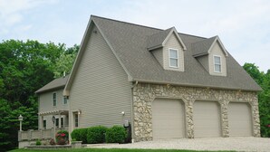 A two-story house with a stone facade, two garage doors, and a well-maintained lawn. - Sunrise Apt. - Peaceful Country Setting- Reasonable Distance to Hocking Hills  (Amanda)