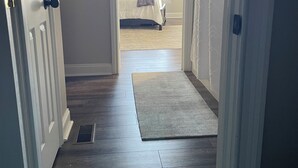 A hallway with a wooden floor leading to a bedroom with a bed and a ceiling fan. - Sunrise Apt. - Peaceful Country Setting- Reasonable Distance to Hocking Hills  (Amanda)