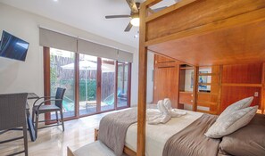 Un dormitorio con una cama grande, un ventilador de techo y un televisor montado en la pared.