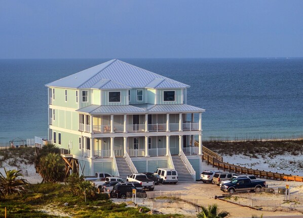 A multi-story beachfront building with a balcony and a staircase leading to the upper floors.