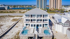 A multi-story hotel with a pool area, balconies, and a view of the beach and ocean.
