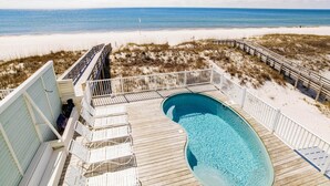 Una terraza de madera con piscina, con vistas a una playa de arena y un océano azul cristalino.