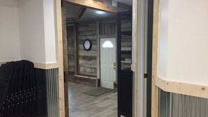 A hallway with a wooden floor, a black radiator, and a clock on the wall.