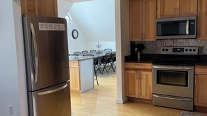 A modern kitchen with stainless steel appliances, wooden cabinets, and a dining area with a table and chairs.
