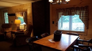 A cozy room with a wooden table, chairs, a lamp, and a window with curtains. - WATERFRONT and AFFORDABLE (Warrensburg)