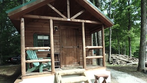 A rustic cabin with a porch, wooden benches, and a small table. - WATERFRONT and AFFORDABLE (Warrensburg)