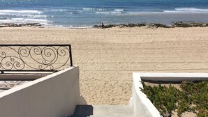 A beach with a staircase leading down to the sand, a railing, and some greenery. - Beach front in Rocky Point (Puerto Penasco)