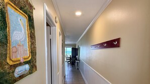 Passadís amb un mur decoratiu, un senyal i una vista d'una habitació amb taula i cadires.