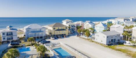 A coastal hotel with multiple buildings, a swimming pool, and a beach view.