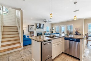 A modern kitchen with a central island, built-in dishwasher, and a dining area with a blue sofa.