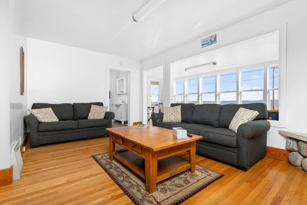 A living room with two dark grey sofas, a wooden coffee table, and a patterned rug. - Kaiser House Sleeps 8, Traverse City 3 minutes away!  Pet friendly   (Traverse City)