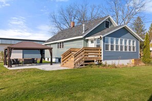 A two-story house with a covered patio, a wooden staircase, and a small deck. - Kaiser House Sleeps 8, Traverse City 3 minutes away!  Pet friendly   (Traverse City)