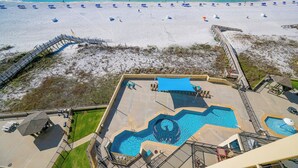 A rooftop pool with a unique design, a beach view, and a deck area with lounge chairs.