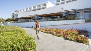 A modern building with a glass facade, outdoor seating areas, and a landscaped walkway. - Club Marmara Doreta Beach Resort & Spa All Inclusive (Rhodes)