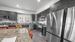 A modern kitchen with stainless steel appliances, granite countertops, and dark cabinetry. - Private Retreat:master suite w Jacuzzi tub,game room,pool,outdoor entertainment! (North Myrtle Beach)