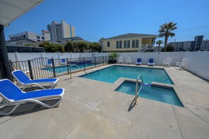 A swimming pool with blue chairs and a white fence, surrounded by a concrete deck. - Private Retreat:master suite w Jacuzzi tub,game room,pool,outdoor entertainment! (North Myrtle Beach)