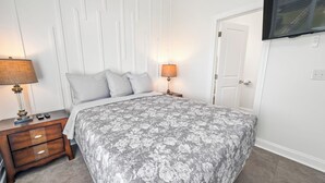 A bedroom with a bed, nightstands, lamps, a TV, and a door. - Private Retreat:master suite w Jacuzzi tub,game room,pool,outdoor entertainment! (North Myrtle Beach)