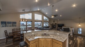 A spacious kitchen with a large island, wooden cabinets, and a dining area with chairs. - Breathtaking Mountain Sunsets! 6BR, 3 King Beds, Hot Tub, Shuttle, Sleeps 16+ (Fraser)