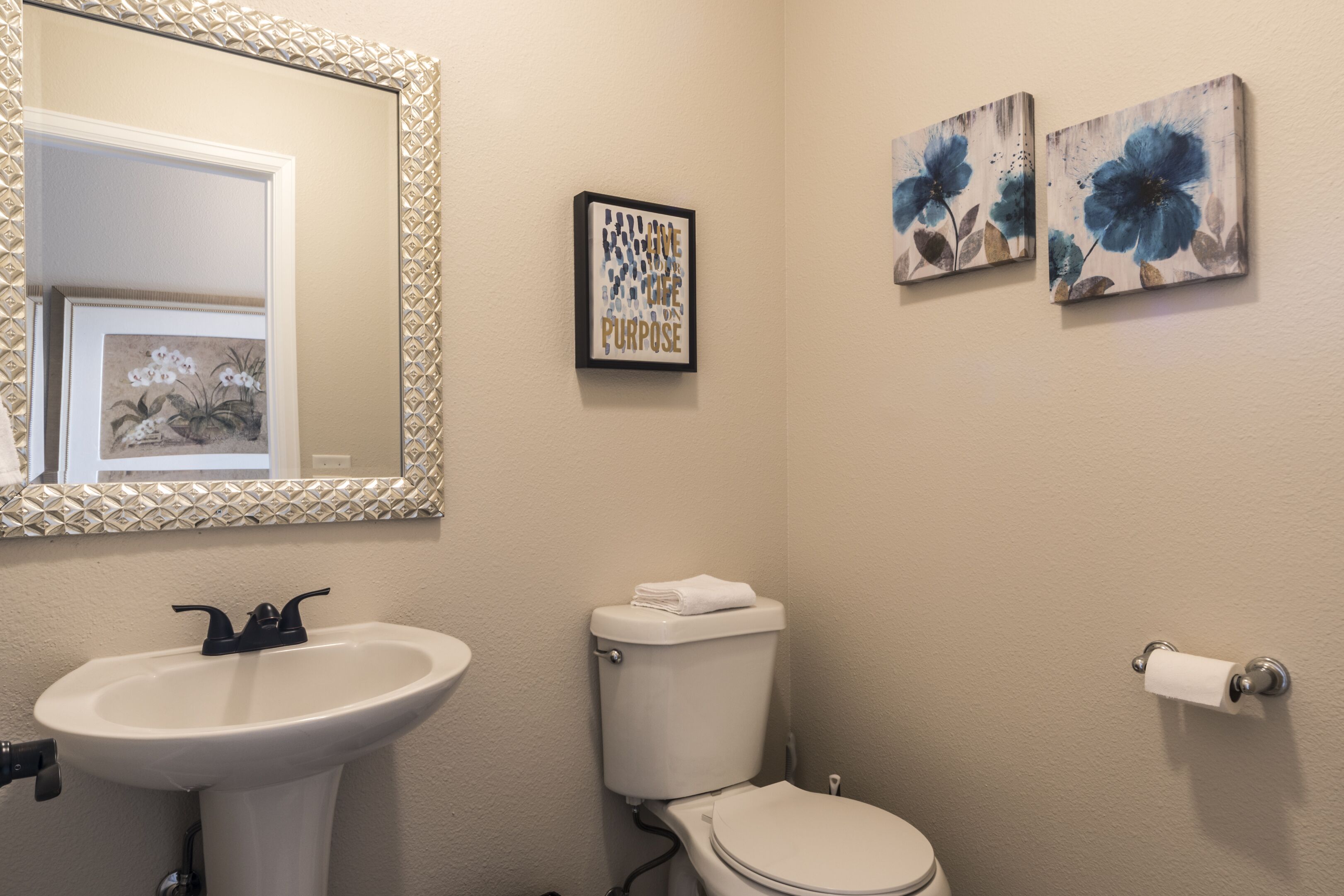 Ein Badezimmer mit Waschbecken, Toilette und zwei floralen Wandbildern.
