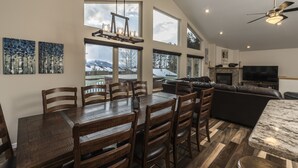 A spacious living area with a large dining table, multiple chairs, a sofa, and a TV. - Breathtaking Mountain Sunsets! 6BR, 3 King Beds, Hot Tub, Shuttle, Sleeps 16+ (Fraser)