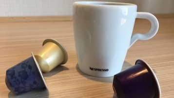 Una tassa blanca de Nespresso i dues càpsules sobre una superfície de fusta.