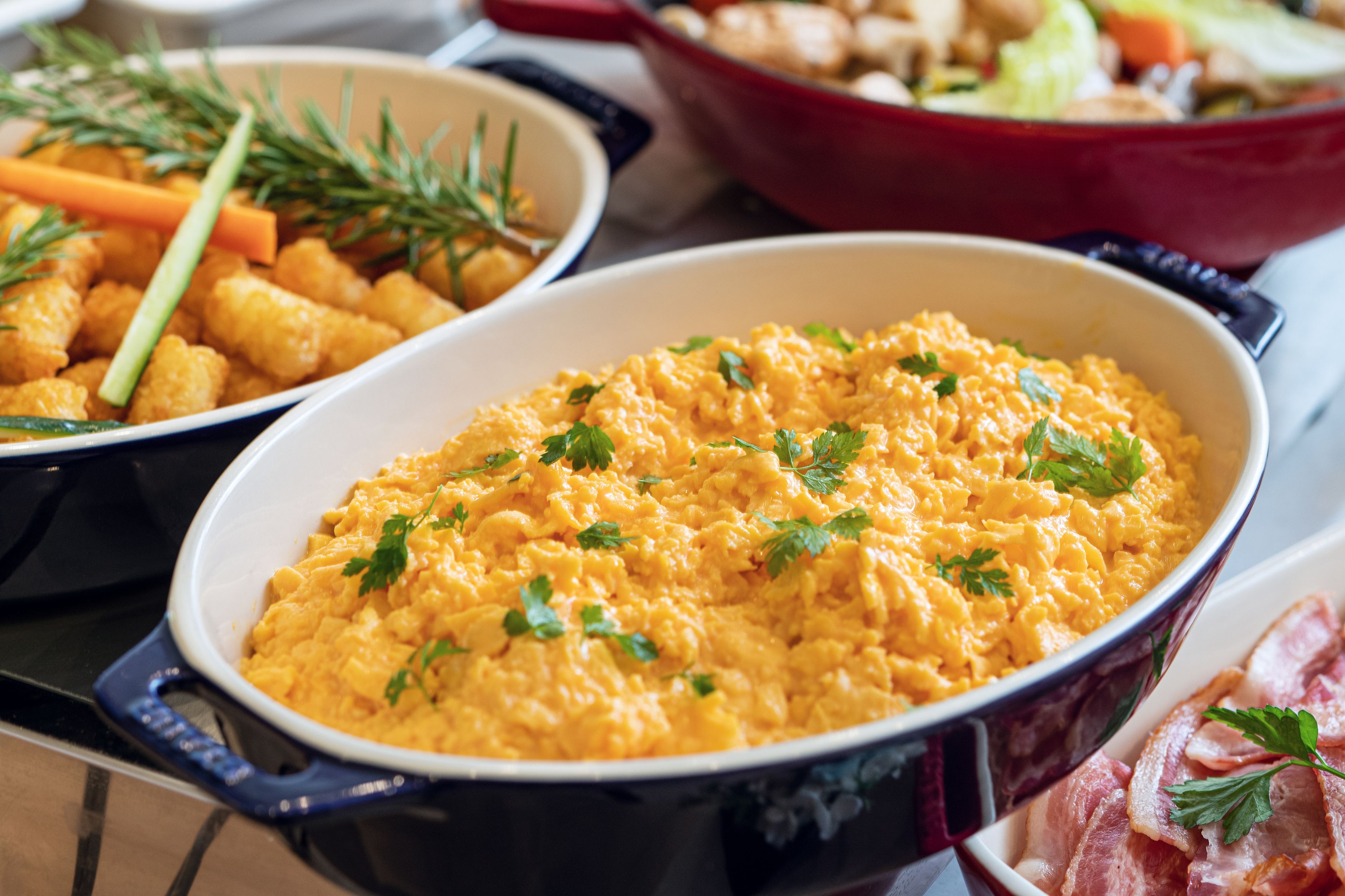 A variety of dishes including scrambled eggs, tater tots, and bacon, suggesting a buffet-style meal.