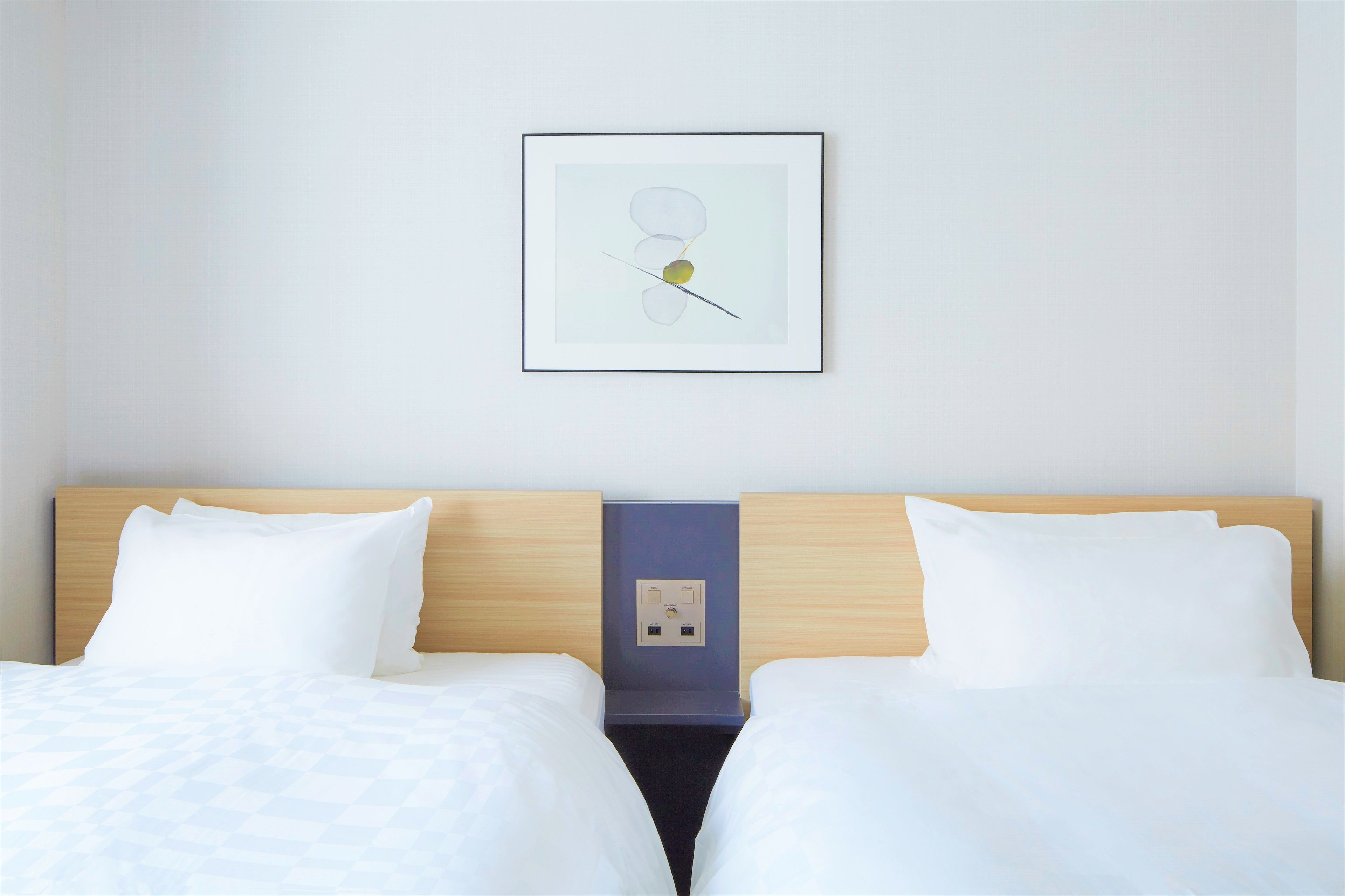 A hotel room with a double bed, a bedside table, a power outlet, and a framed picture on the wall.