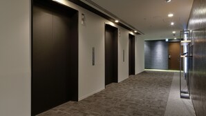 A modern hallway with three elevator doors, carpeted flooring, and recessed lighting. - Tmark City Hotel Tokyo Omori (Tokyo)