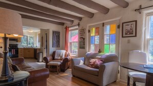 A cozy living room with a fireplace, a dining table, and a kitchen in the background. - Adobe House on Taylor River | 3 Bedroom | River Access | Gas Grill | Yard (Almont)