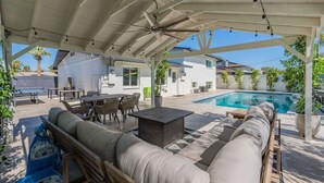 An outdoor patio area with a pool, seating, and a covered section.