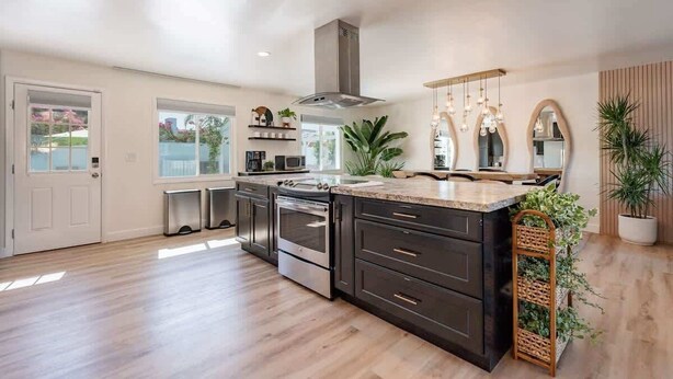 A spacious kitchen with dark cabinetry, stainless steel appliances, and a large island.