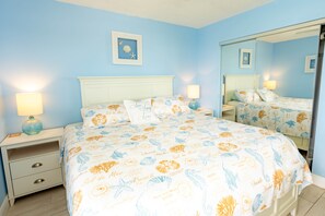 A bedroom with a bed, nightstands, a dresser, and a large mirror.