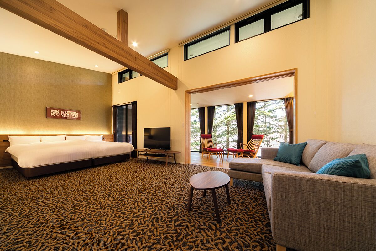 A spacious bedroom with a large bed, a TV, and a seating area with a sofa and chairs.